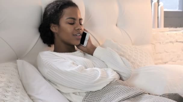 Giovane donna africana che parla al telefono mentre si rilassa a letto — Video Stock