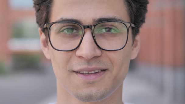 На відкритому повітрі крупним планом усміхнений молодий чоловік в окулярах — стокове відео