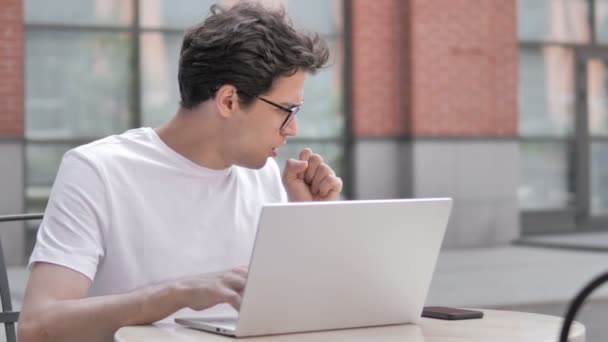 Joven enfermo tosiendo mientras trabaja en el ordenador portátil al aire libre — Vídeo de stock