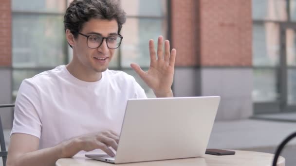 Chat vidéo en ligne sur ordinateur portable par jeune homme assis en plein air — Video