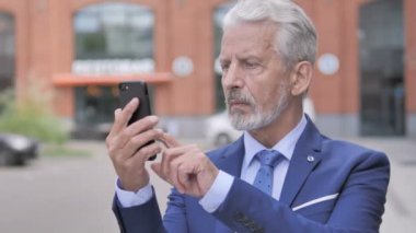 Smartphone kullanan Eski İşadamının Açık Hava Portresi