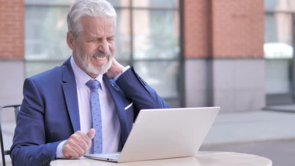 Уставший старый бизнесмен с болью в шее, работающий над ноутбуком, на открытом воздухе — стоковое видео