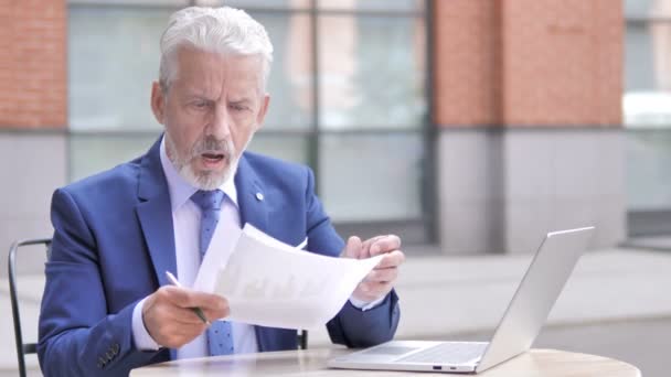 Viejo hombre de negocios molesto mientras lee documentos, al aire libre — Vídeo de stock