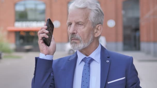 Buiten portret van oude zakenman praten op telefoon — Stockvideo