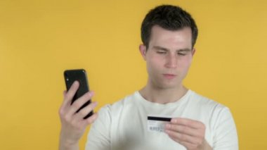 Sarı Arka Plan izole Smartphone üzerinden Genç Adam tarafından Online Alışveriş