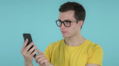 Genç Adam Mavi Arka Plan da İzole Smartphone Kullanırken Başarı Için Heyecanlı