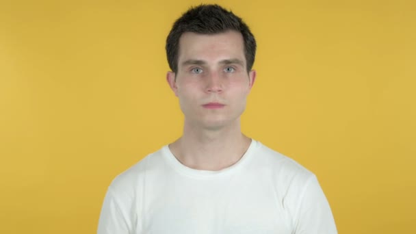 Молодий чоловік жестикулює великі пальці вниз ізольовані на жовтому тлі — стокове відео