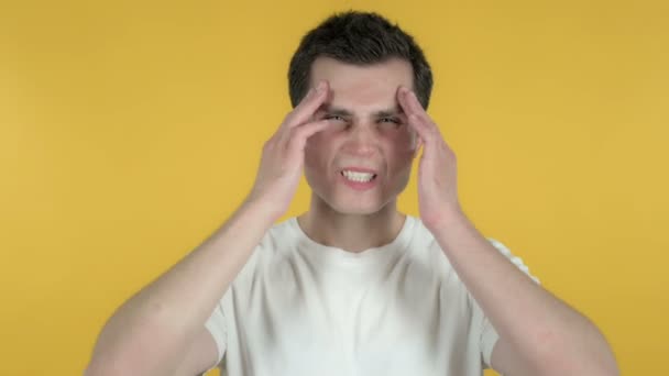 Hombre joven con dolor de cabeza aislado sobre fondo amarillo — Vídeos de Stock