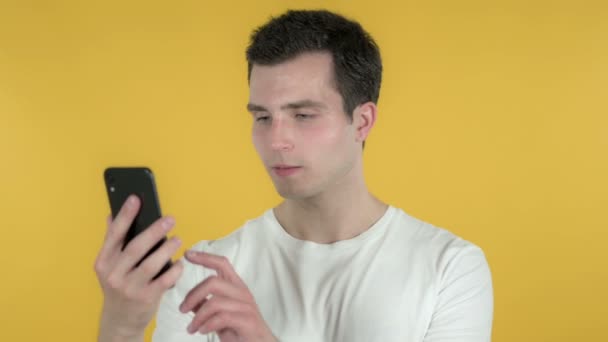 Jovem animado para o sucesso ao usar Smartphone isolado em fundo amarelo — Vídeo de Stock