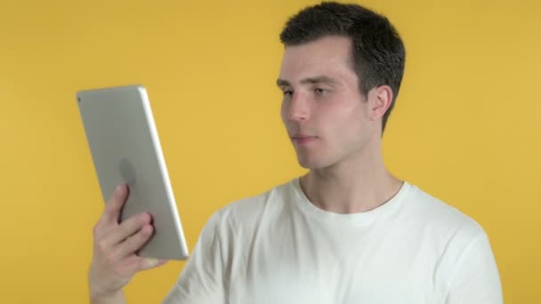노란 배경에 고립 된 태블릿을 사용하는 동안 성공을 위해 흥분한 젊은 남자 — 비디오