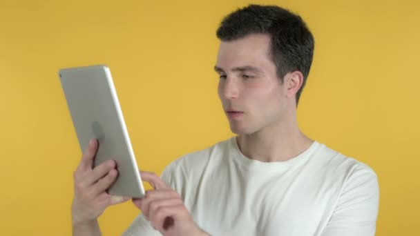 Hombre joven reaccionando a la pérdida en la tableta aislado sobre fondo amarillo — Vídeo de stock