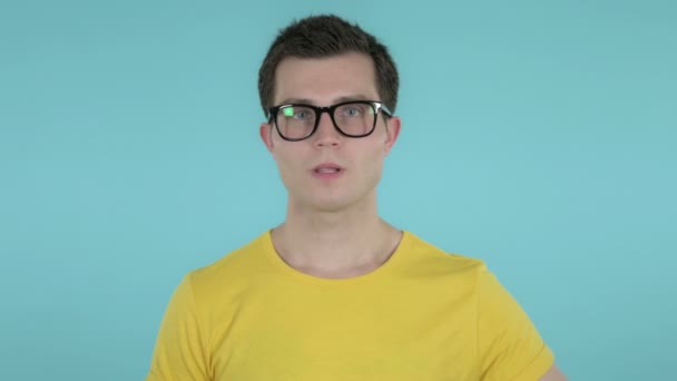Молодой человек Gesturing Thumbs Down изолирован на синем фоне — стоковое видео