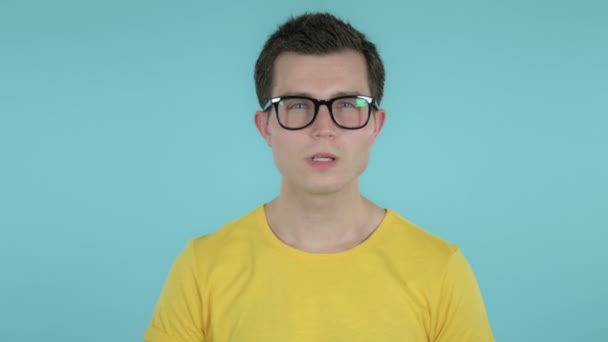 Jonge man wijst op de camera geïsoleerd op blauwe achtergrond — Stockvideo
