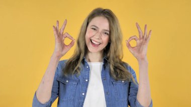 Tamam işareti genç güzel kız sarı zemin üzerine