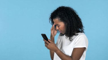 Afrikalı kız şok kullanma Smartphone izole mavi arka plan üzerinde iken