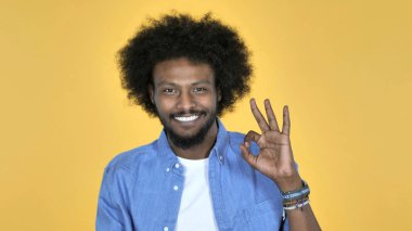 Sarı arka plan üzerinde izole rahat Afrika adam Tamam işareti