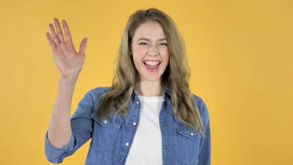 Jovem menina bonita acenando mão para Bem-vindo no fundo amarelo — Fotografia de Stock