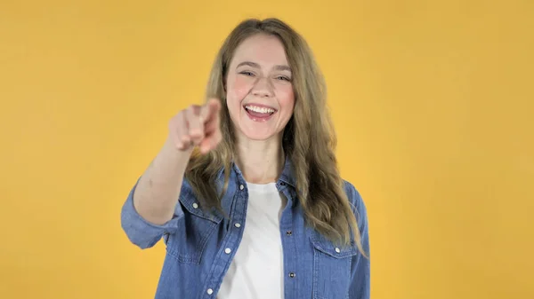 Menina bonita jovem apontando para a câmera no fundo amarelo — Fotografia de Stock