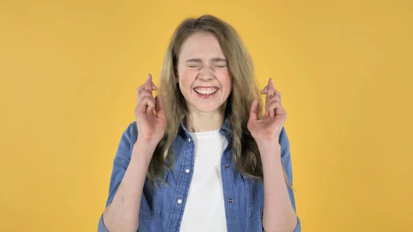 Finger korsade av Young leende vacker flicka på gul bakgrund — Stockfoto