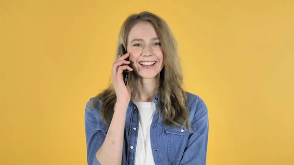 Menina bonita jovem falando no smartphone em fundo amarelo — Fotografia de Stock