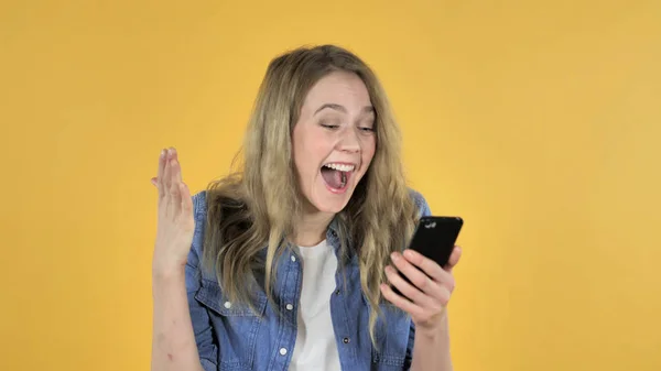 Young Pretty Girl Excited for Success while Using Smartphone on Yellow Background — Stock Photo, Image