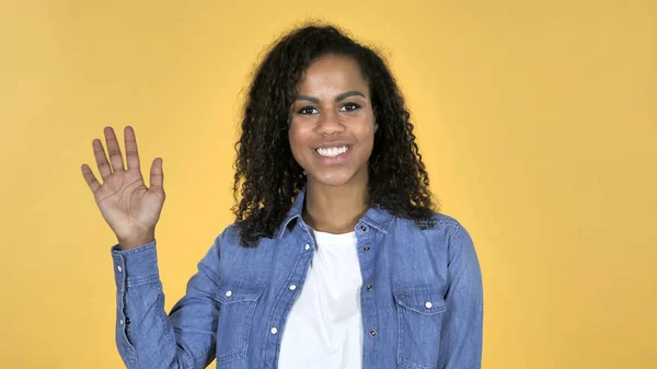 Africano menina acenando mão para bem-vindo isolado no fundo amarelo — Fotografia de Stock