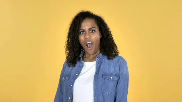 Amazed African Girl Surprised while Truing Around Isolated on Yellow Background