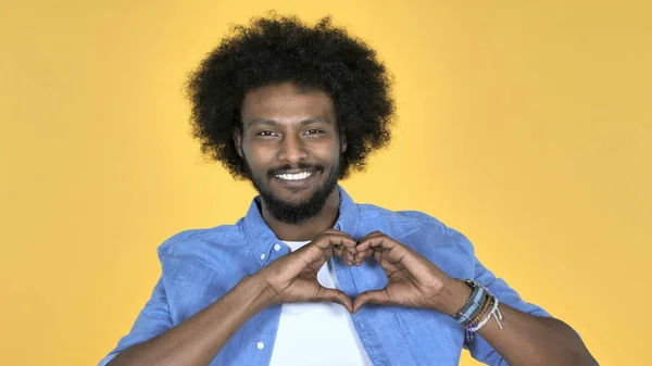 Corazón hecho a mano por el hombre africano casual aislado sobre fondo amarillo —  Fotos de Stock