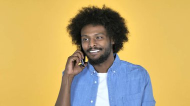 Afro-American Man Talking on Smartphone on Yellow Background clipart