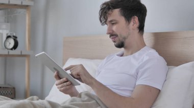 Genç adam kullanarak Tablet Lying yatakta iken