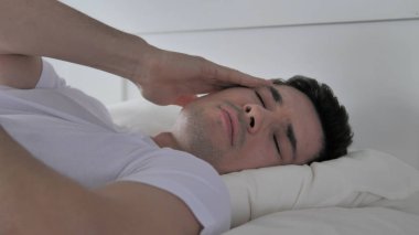 Baş ağrısı, huzursuz genç adam yatakta uyuyor