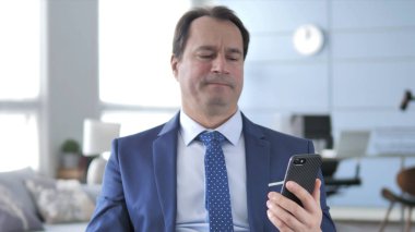 Orta yaşlı işadamı tepki Smartphone kullanarak süre kaybı