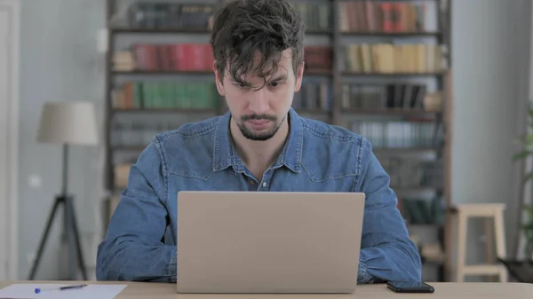 Молодой человек работает на ноутбуке в офисе — стоковое фото