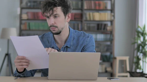 Papírování, mladý muž psaní na notebooku a práce s dokumenty — Stock fotografie