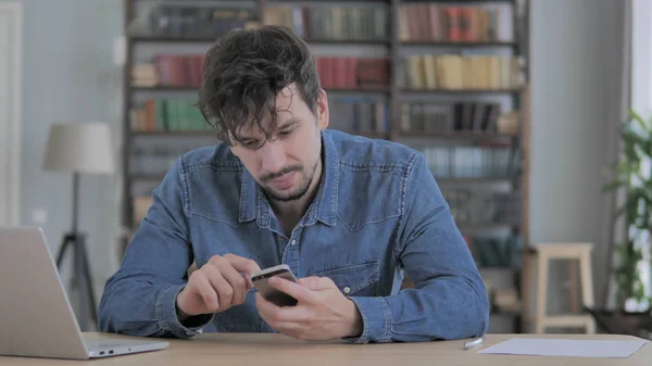 Человек с помощью смартфона, просмотр онлайн на работе — стоковое фото
