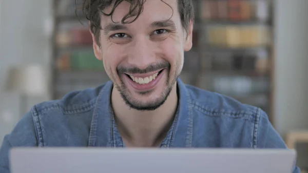 Lächelnder junger Mann bei der Arbeit, der in die Kamera schaut — Stockfoto