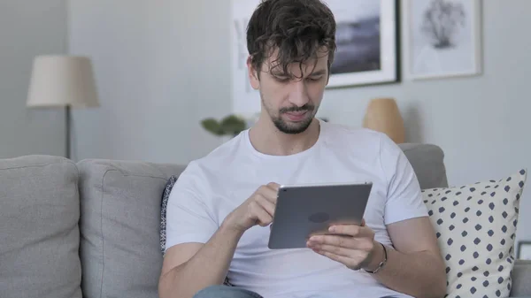 Молодой человек использует планшет, расслабляясь дома — стоковое фото