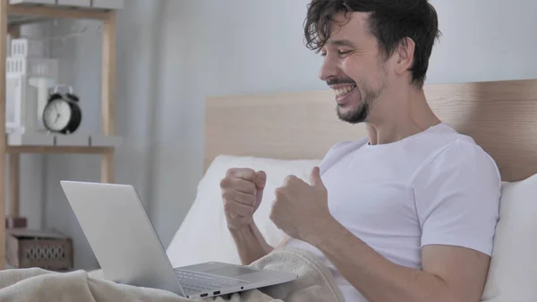 Happy Man Celebrating Success while using Laptop in Bed — стоковое фото