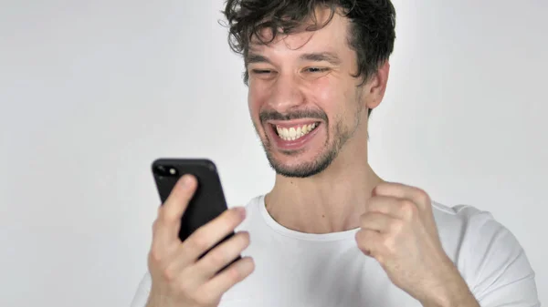 Joven hombre casual emocionado por el éxito mientras se utiliza el teléfono inteligente —  Fotos de Stock