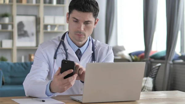 Lekarz pracuje na laptopie i przy użyciu smartfona — Zdjęcie stockowe