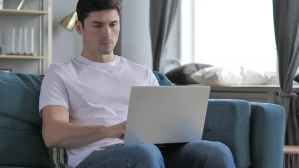 Случайный молодой человек, работающий с ноутбуком в мышцах — стоковое фото