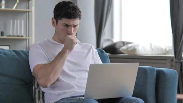 Zieke jonge man hoesten tijdens het werken op laptop — Stockfoto
