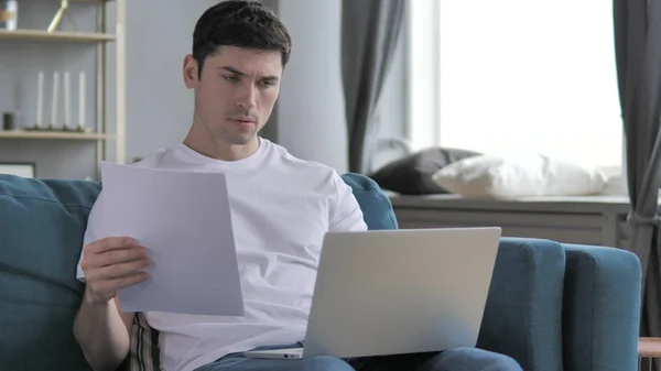 Jonge man werken aan documenten en laptop, papierwerk — Stockfoto