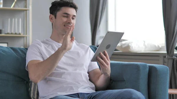 Online videokonverzace prostřednictvím tabletu relaxace mladého muže — Stock fotografie