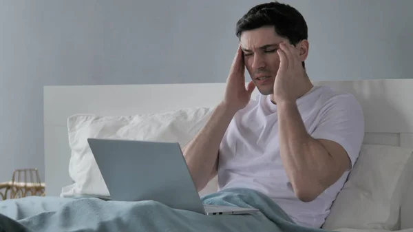 Mal di testa, tensione giovane che lavora sul computer portatile a letto — Foto Stock