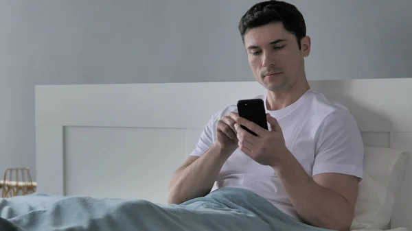 Молодой человек просматривает смартфон, используя Интернет — стоковое фото