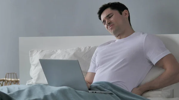 Junger Mann mit Rückenschmerzen sitzt im Bett — Stockfoto