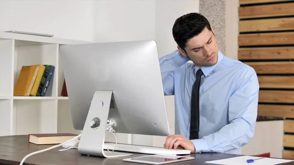 Giovane uomo d'affari con dolore al collo che lavora su computer, tirare il muscolo — Foto Stock