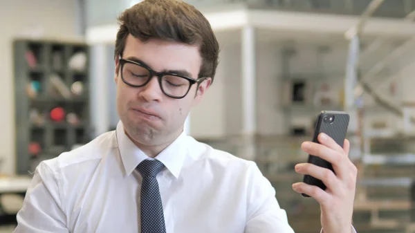 Молодой бизнесмен реагирует на убытки на смартфоне — стоковое фото
