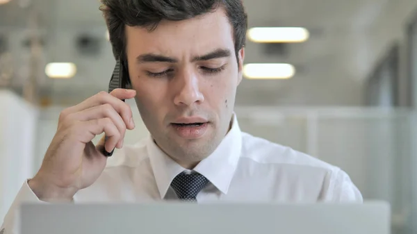Empresario hablando por teléfono y trabajando en el ordenador portátil, Vista frontal — Foto de Stock